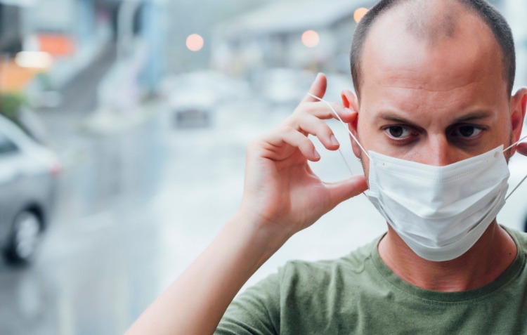 mannen sätter en skyddsmask på ansiktet under pandemi