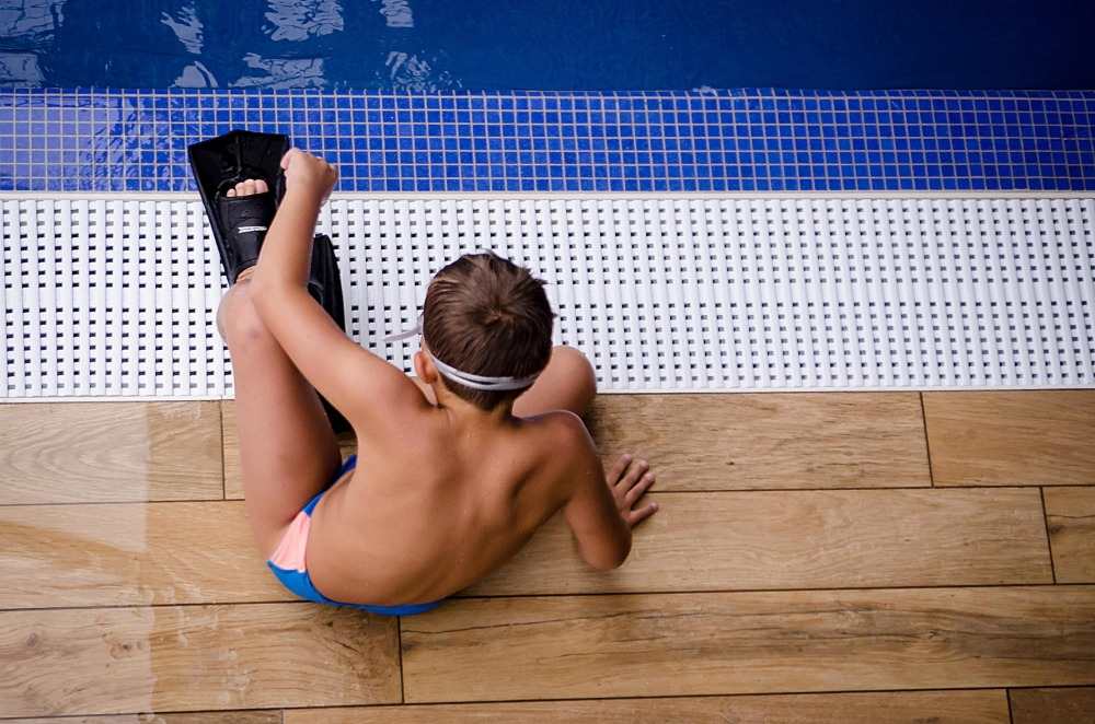 pojke med simfenor och baddräkt förbereder sig för simning i poolen