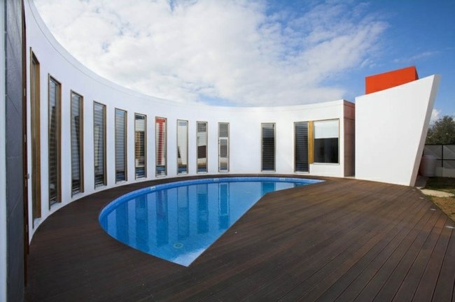 Glasfiberpool delvis täckt modern terrasshus i trä