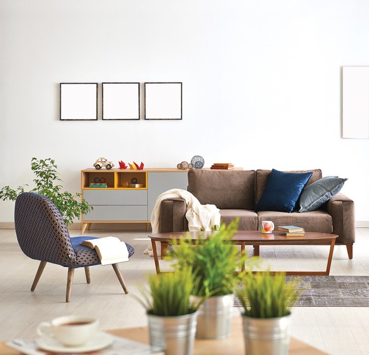 En elegant och glest möblerad lägenhet med vita väggar, en soffa, ett soffbord, en stol, en skänk, växter och en kopp kaffe i förgrunden