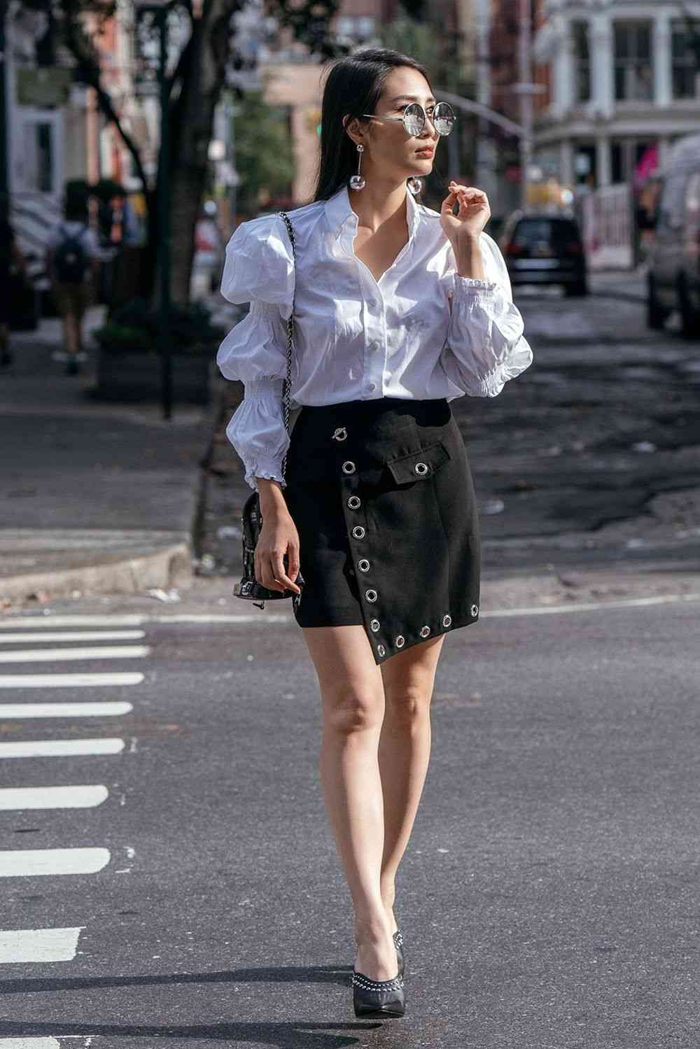 Skjortblusens puffärmar kombinerar svart minikjol med höga klackar, solglasögon runda