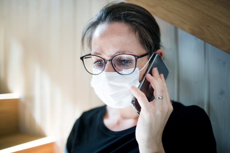 Bekymrad kvinna i skyddsmask ringer läkare under pandemi covid 19