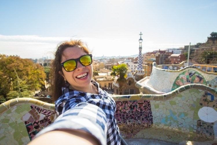 ung kvinna med solglasögon gör selfie i parkguell med utsikt över staden barcelona på hösten