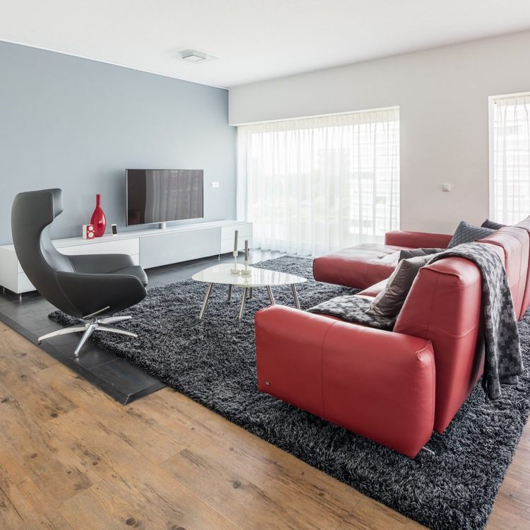 Röd soffa läder-vardagsrum-sten grå-väggfärg-antracit-matta-trägolv