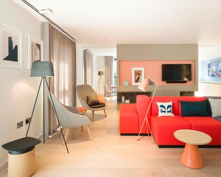 röd-soffa-ljus-trä-golv-beige-gardiner-grå-väggfärg