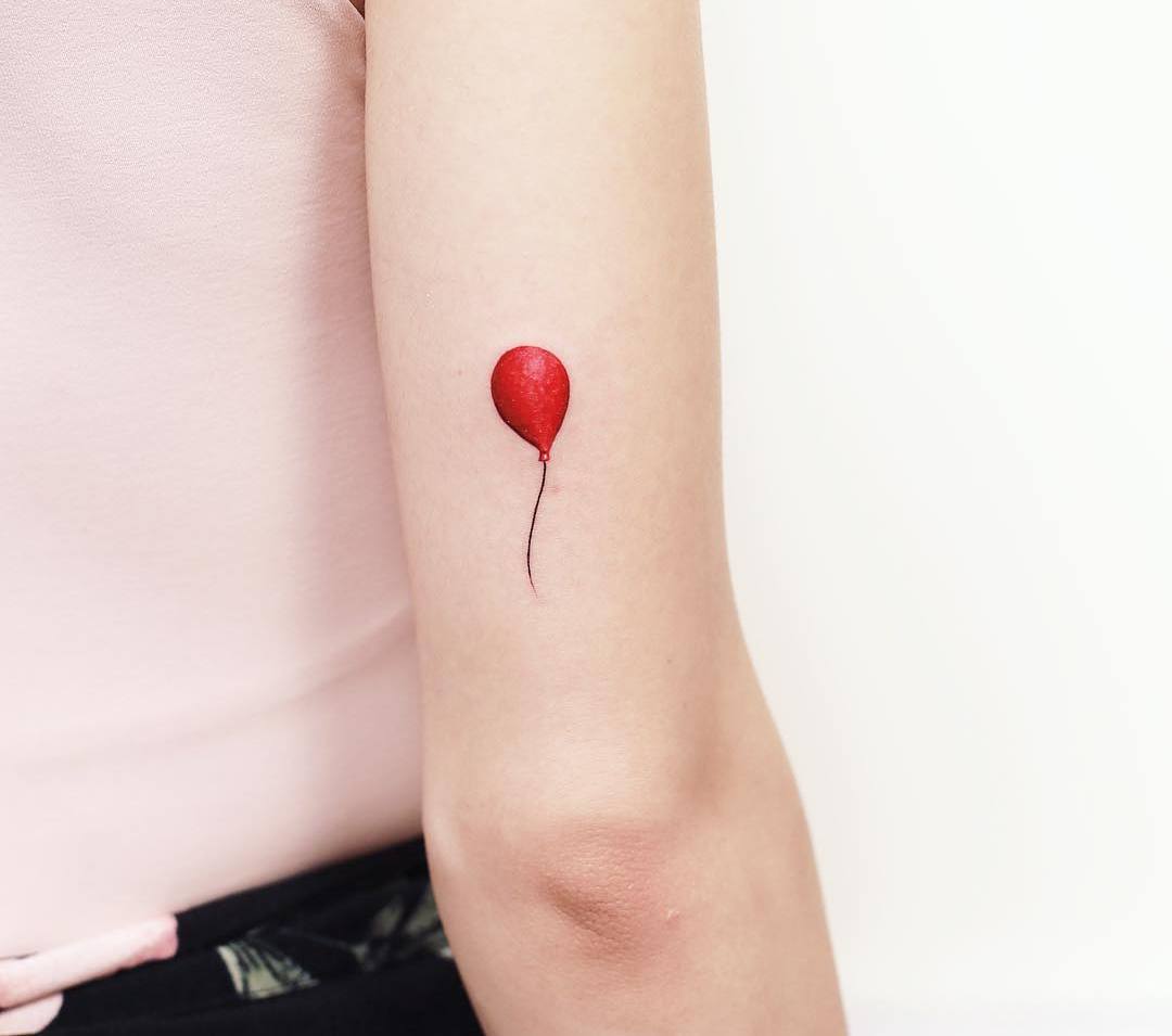 Mini röd ballongtatuering på baksidan av överarmen