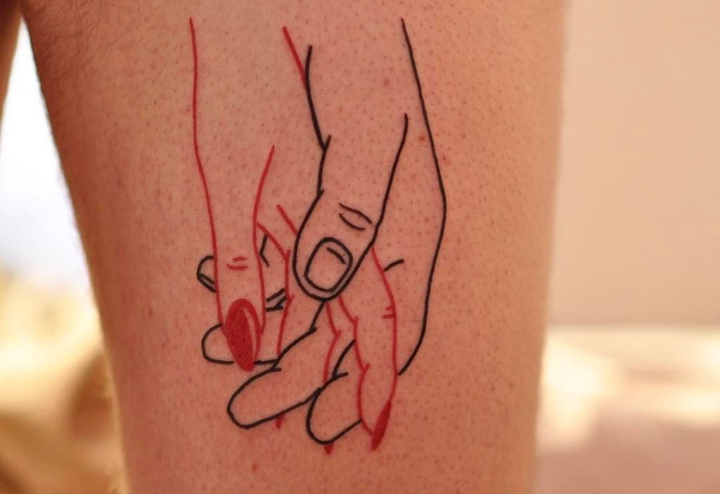 Tatueringsidé med händerna på ett par älskare i rött och svart på låret