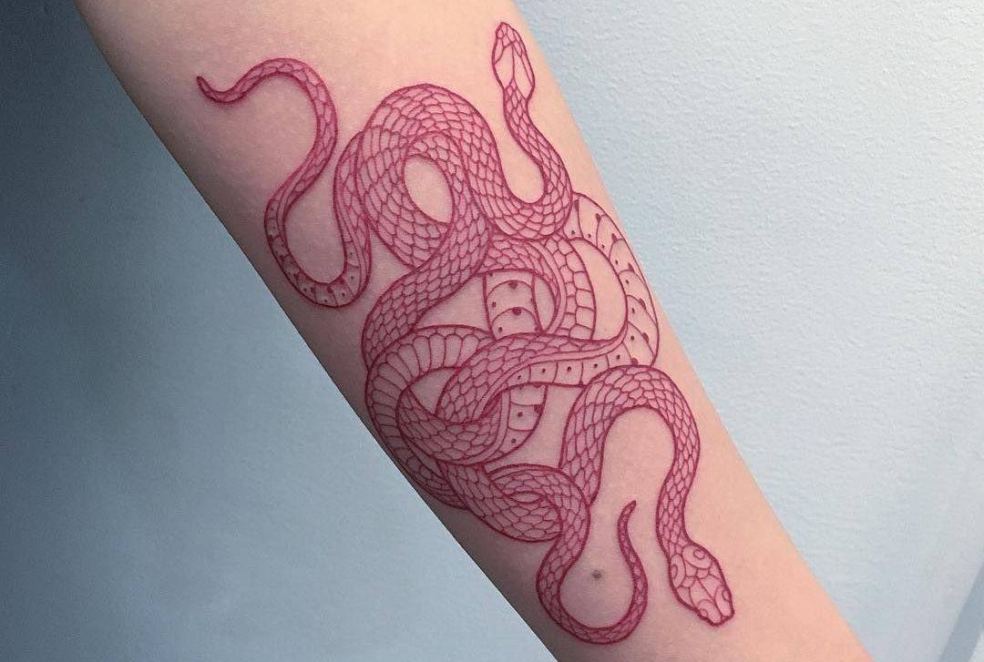 Två vridande ormar av röd färg på underarmen