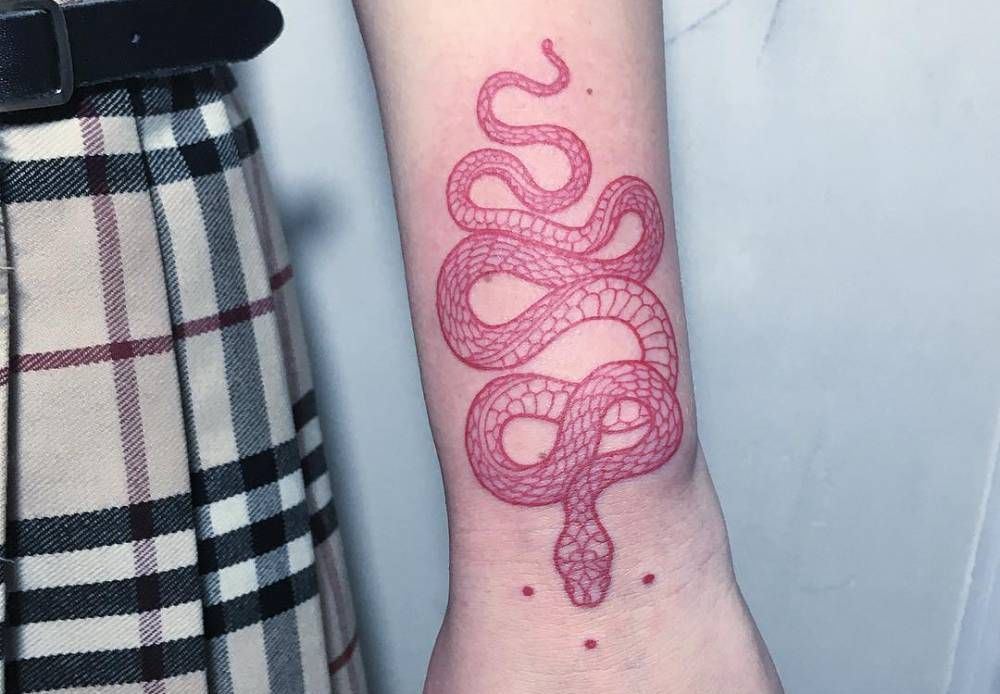 En slingrande orm i rött som en underarmstatuering för kvinnor