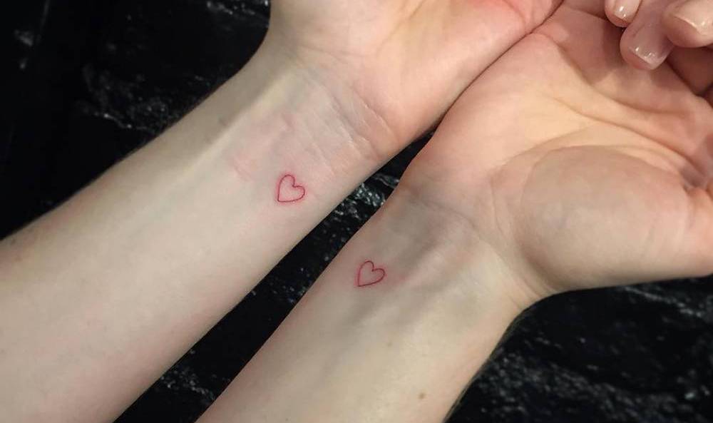 Mikrotatuering med röda hjärtan på handleden som en idé för partners tatueringar