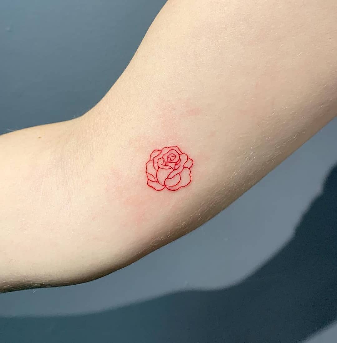 Rose i rött som en minitatuering på armen med ett abstrakt utseende