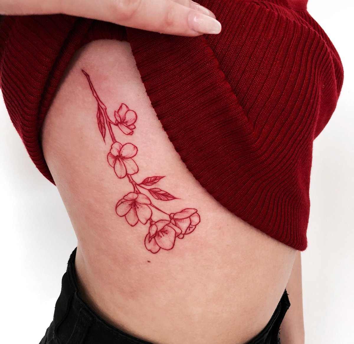 Röda tatueringar för kvinnor med blommor på bröstkorgen