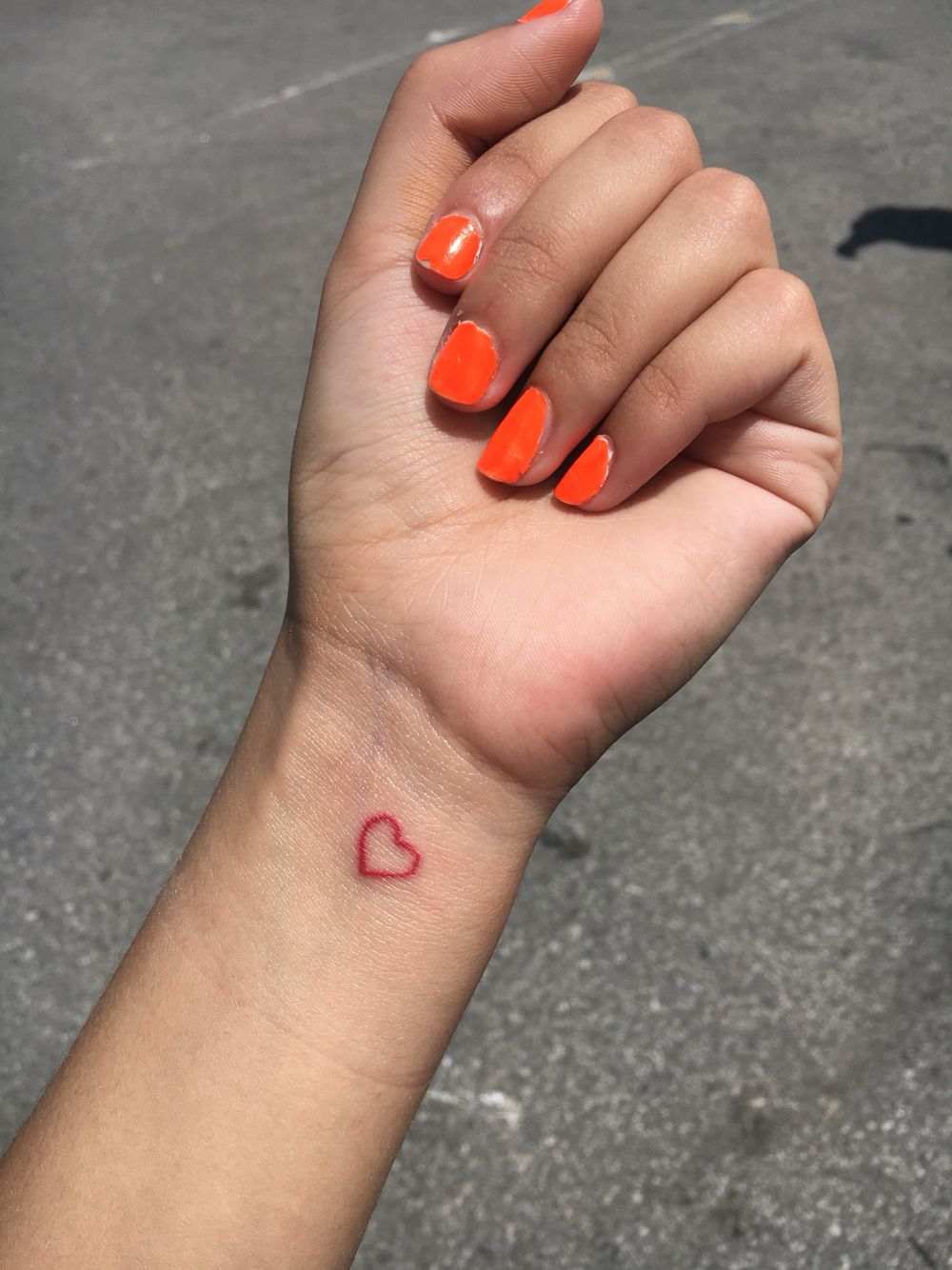 Små röda tatueringar med en idé för ett hjärta på handleden