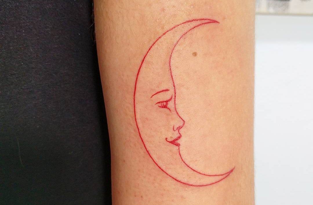 Enkel, skärmformad måne med ett ansikte i röd färg
