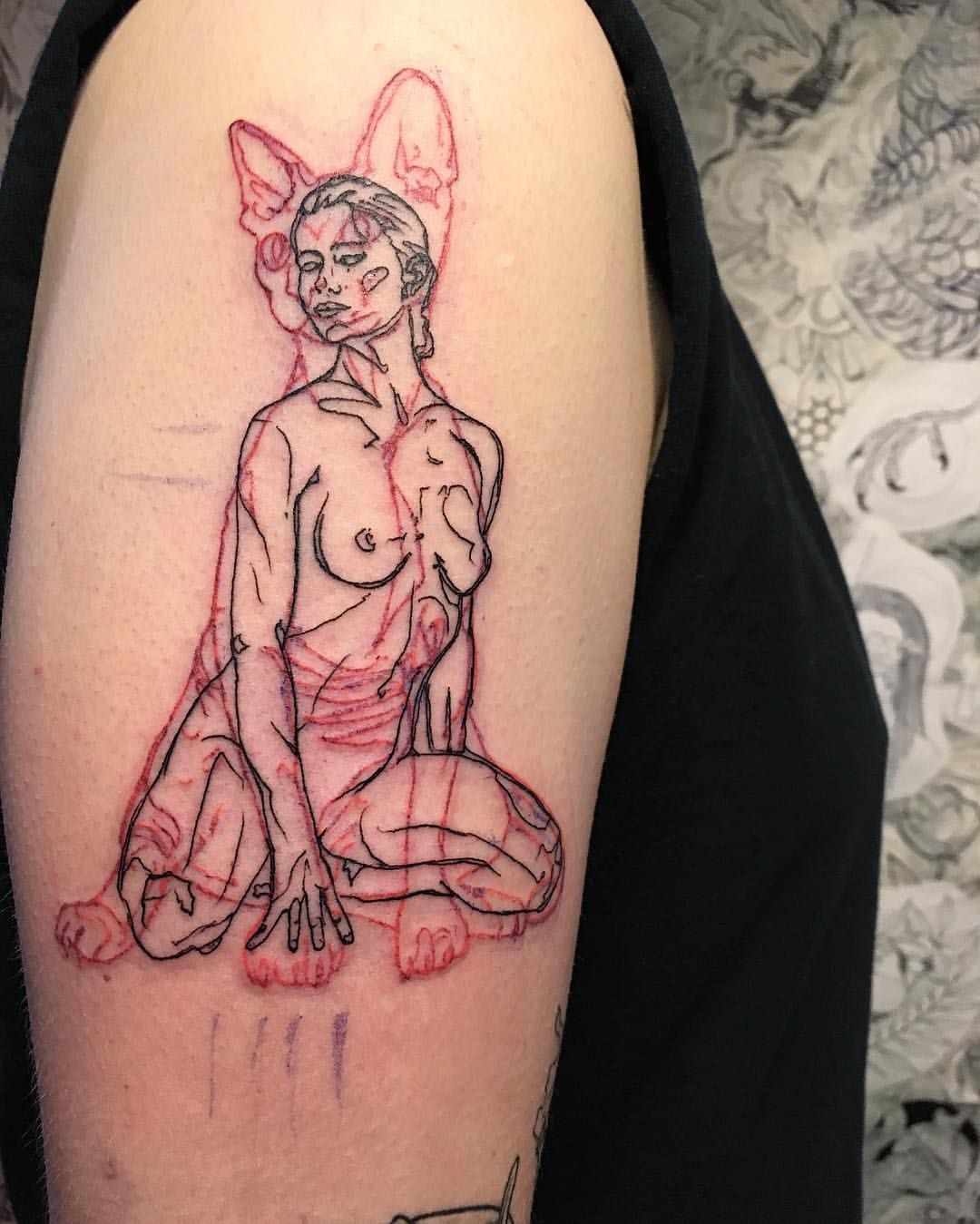 Kombinerar svarta och röda tatueringar - naken kvinna med katt i bakgrunden