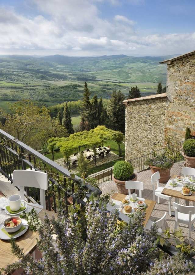 Toskansk hotell med utsikt över terrassen mellan vinmarker och metallräcken Monteverdi
