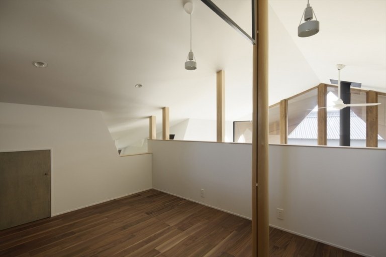 Rum under sluttande tak med trägolv och vita väggar