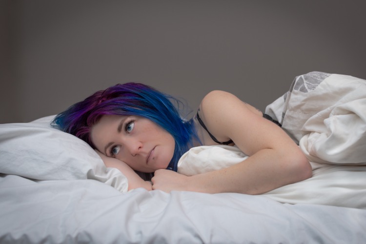 tonårspojke med färgat hår ligger oroligt i sängen på grund av personlighetsstörning