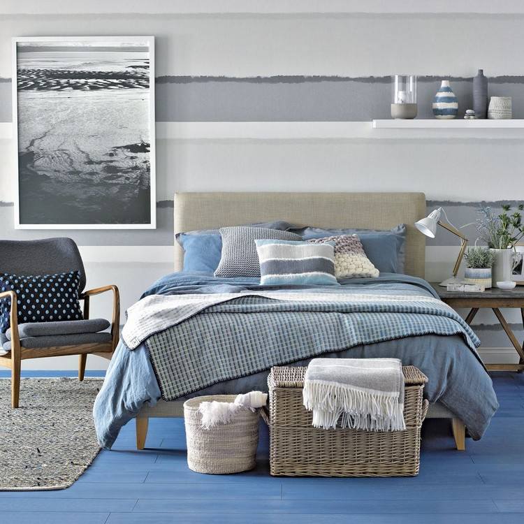 Maritimt sovrum målar sandfärg och blå ränder på väggen bakom rottingbädden
