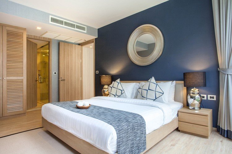 Måla mörkblå vägg och dekorera sovrummet med äkta trämöbler av ek