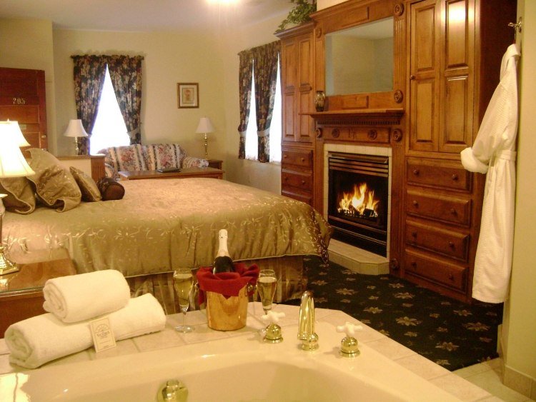 sovrum-bubbelpool-säng-öppen spis-trä vägg-lyx-överkast-guld-mousserande vin-hotellrum-romantisk