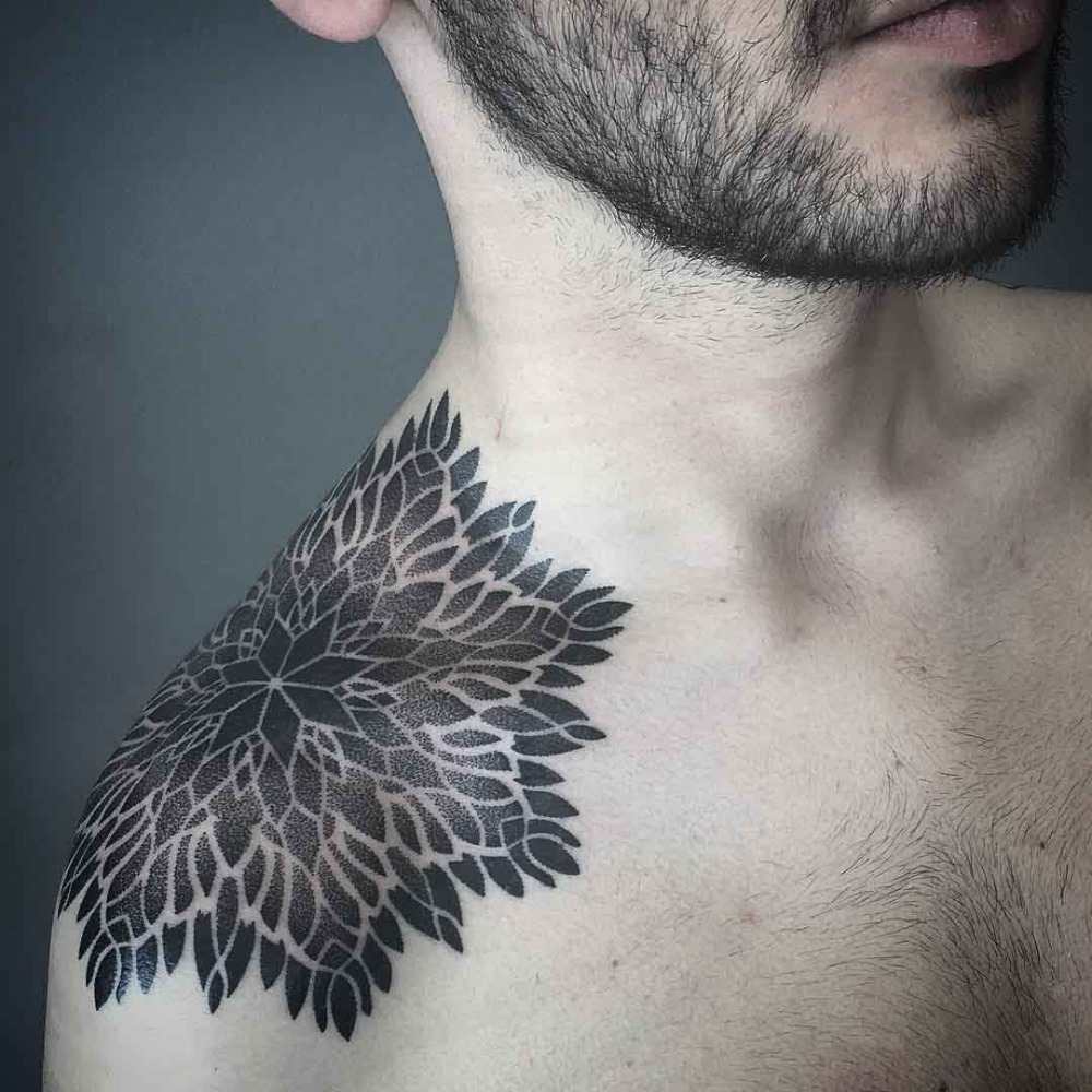 man med blommönster tatuering på axeln tatuerad med svart bläckfärg