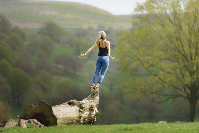 blond kvinna med jeans står på ett träd och försöker hoppa
