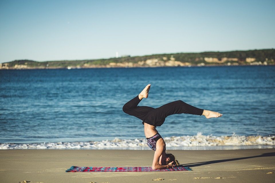 kvinna som gör yoga på stranden under dagen vid havet