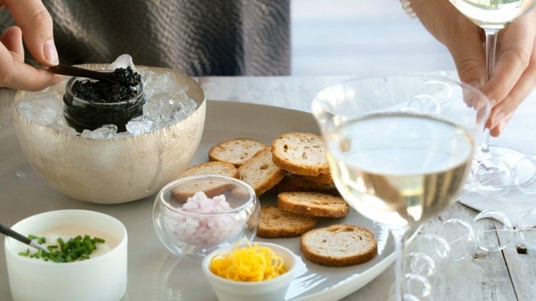 Svart kaviar servering på sängen av isbröd toast vin serveringsbricka