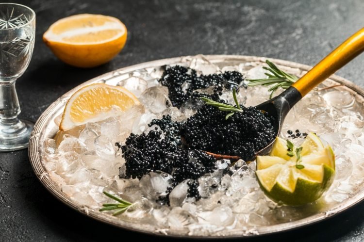 Svart kaviar serveras på en bädd av is Silberbestevk citroner