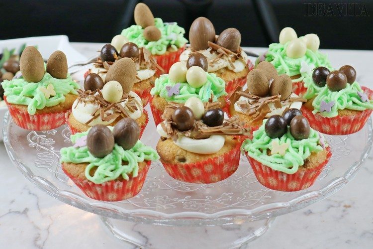 Påskbo cupcakes dekorerade med glasyr och chokladägg serveras på ett glasbricka