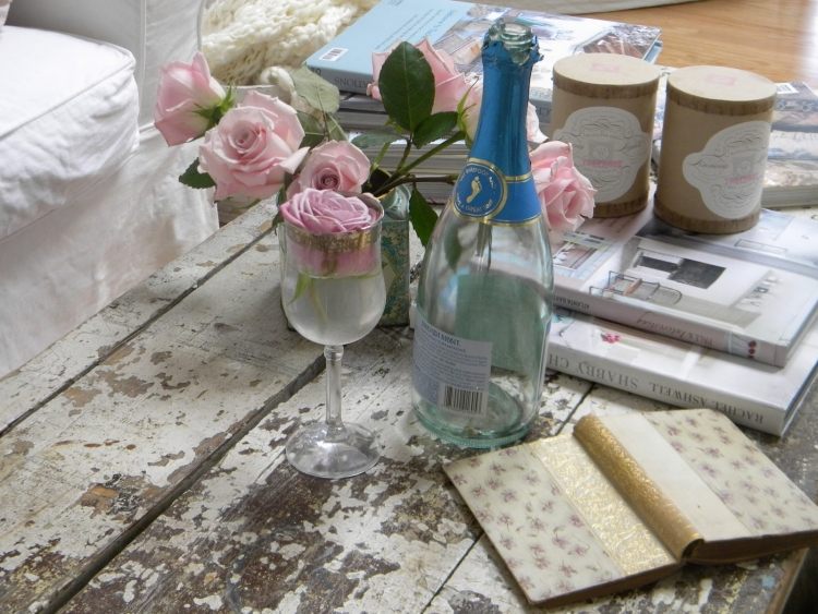 shabby-chic-vardagsrum-dekoration-skalad-av-färg-soffbord-helig-champagne-flaska-ros-vas
