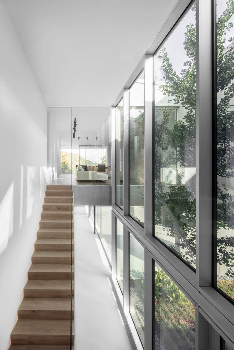 exponerat betonghus casa mf stora glasfönster modern minimalistisk design trappa träsoffa övervåning trädgård första våningen