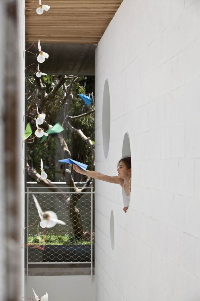 exponerad betong-inuti-vägg-vit-rund-fönster-papper-flygplan-barn-spel