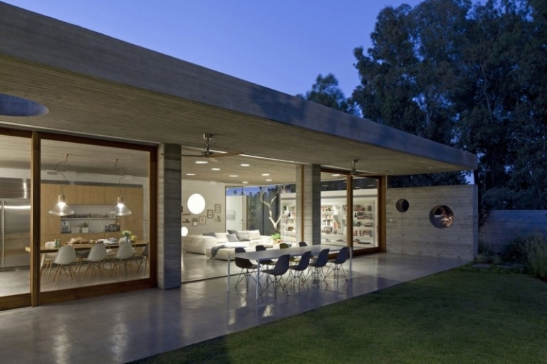 Ljust betong inuti-hus-arkitekt-hus-trädgård-utanför-kväll-matbord-stolar