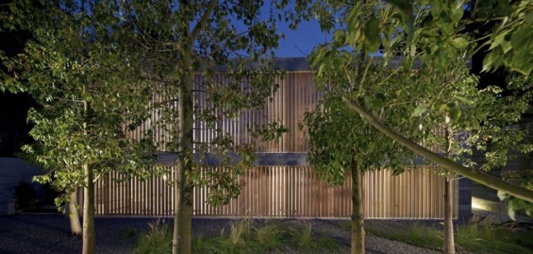 exponerad betong-interiör-arkitekt-hus-kväll-trädgård-träd-belysning-växter