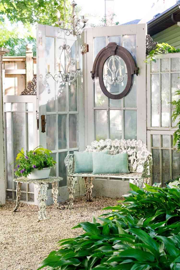 vintage designträdgård i vitt med gamla franska dörrar och soffa med soffbord av järn