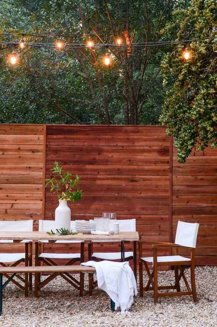 snyggt trädgårdsbord mysigt med ett staket av trälister och lampor