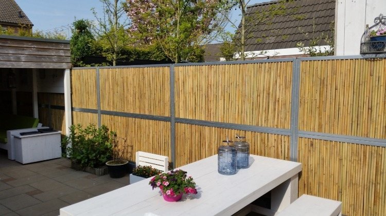 Hemmagjort bambustängsel på gården med garage och vitt bord på sommaren