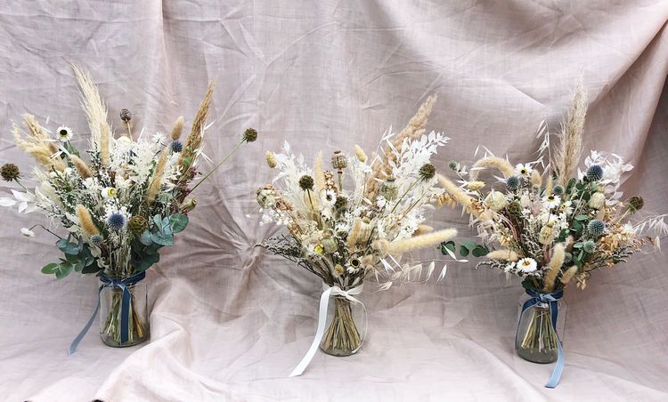 Blomsterarrangemang i glasvaser med torkade blommor