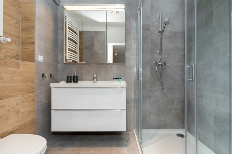 Golvdusch med duschkar och minimalistiskt handfat i det lilla badrummet