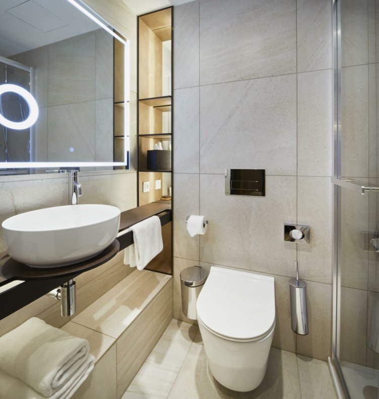 Modern möblerad gästtoalett med dusch - ljusa kakelplattor och våtrum