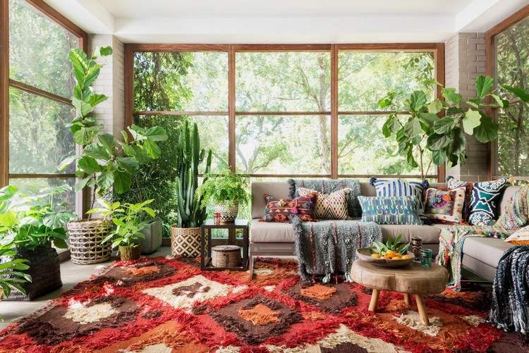 soffa framför fönstret hörnsoffa vardagsrum färgglada kaktusar och succulenter vävda mattor geometriska former träram bohemisk stil