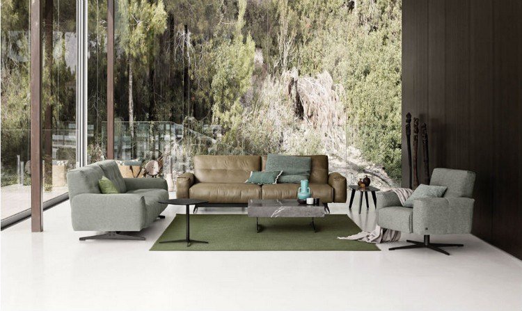 soffa framför fönstret hörnsoffa vardagsrum naturliga färger natur grön matta boho stil tak högt