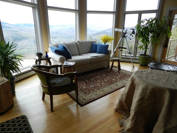 Ställ upp soffa framför fönstret vardagsrum snygg soffa orientalisk matta palmträd teleskop teleskop utsikt berg