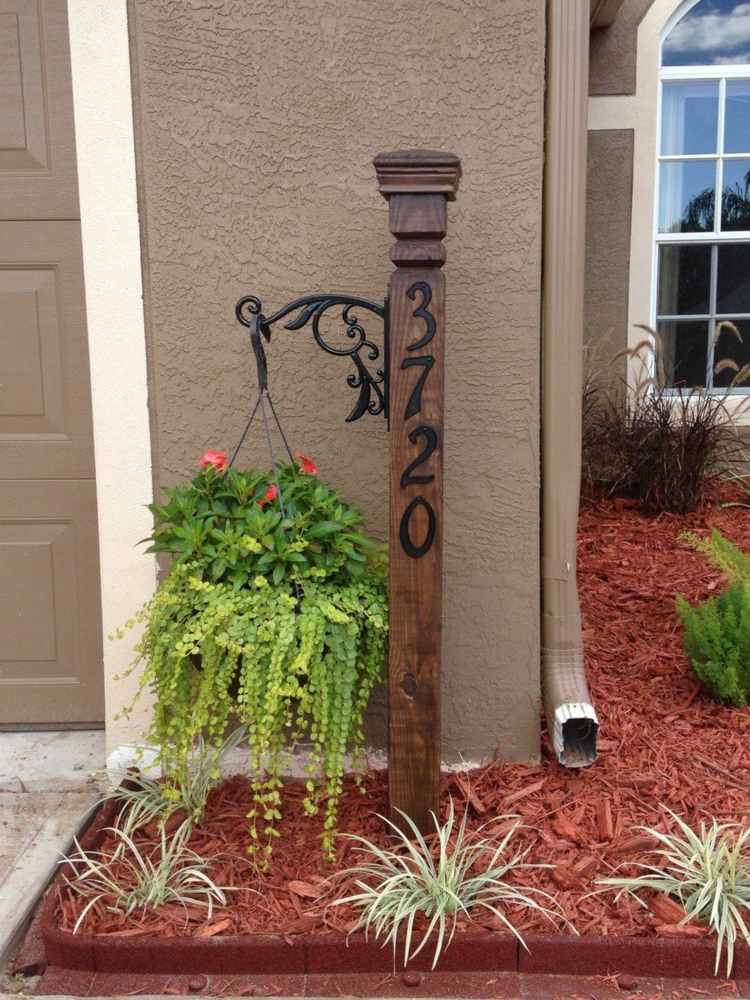 Idé till skylten med husnumret - träbjälkar av ett räcke med krokar för hängande blomkrukor
