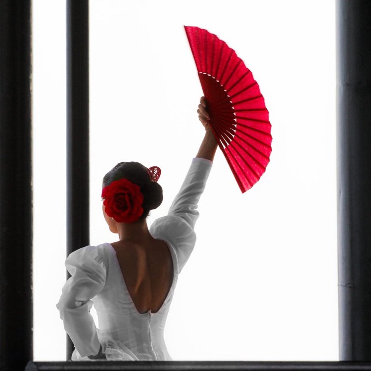 Flamencodansare med en vit klänning och en röd fläkt i handen