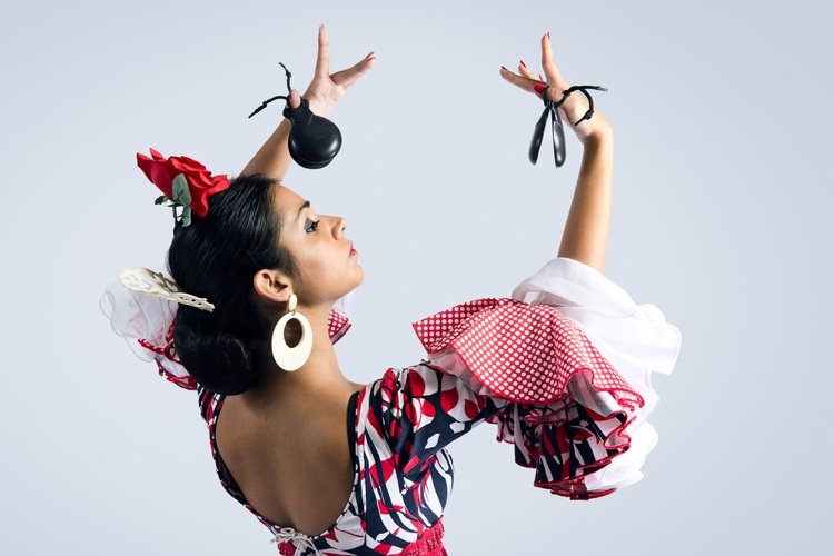 Flamencodansarkostym med stora örhängen och kastanjer i händerna