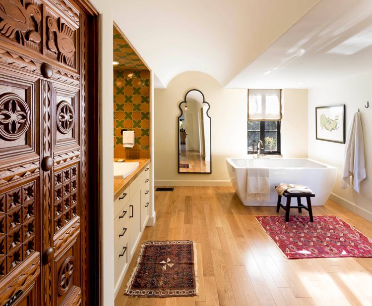 Spanska badrumsinrättningar för badrumsskåp med träsnideri och fristående badkar och kilim- och mosaikplattor och marockansk spegel