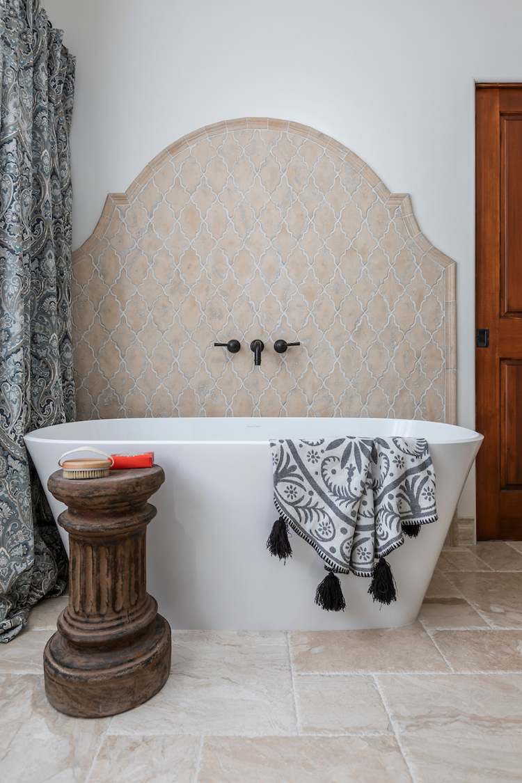 Modernt badrum i spansk stil med natursten på golvet och fristående badkar